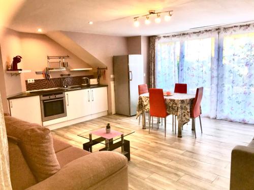 a living room with a kitchen and a table with red chairs at Villa Paraisos in Fuengirola