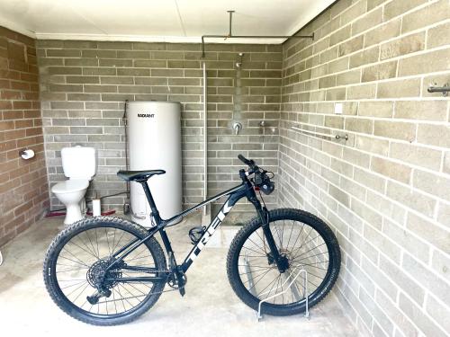 a bike parked in a bathroom with a brick wall at 3 Beaches Cottage in Surf Beach