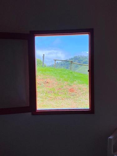 a window in a room with a view of a field at Pousada Vale das Araucárias in Santo Antônio do Pinhal