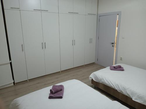 due letti in una stanza con armadi bianchi e asciugamani viola di Premium Square Apartment a Skopje