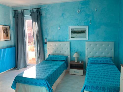 ein blaues Schlafzimmer mit zwei Betten und einem Fenster in der Unterkunft Villa Marina in Orosei