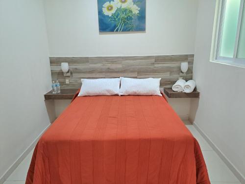 a bedroom with a bed with an orange blanket at Hotel Anturio in Dolores Hidalgo