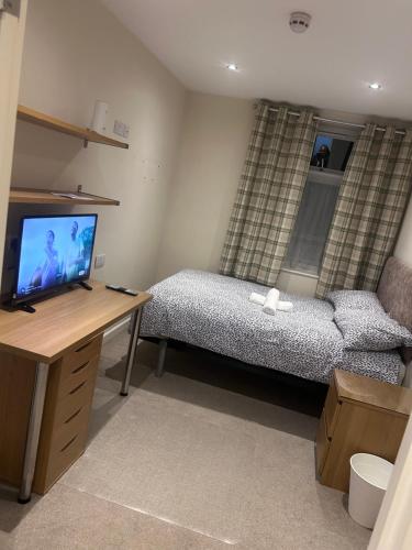 a bedroom with a bed and a desk with a television at Seaford Guest House XXX in Stoke on Trent