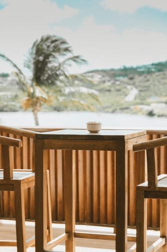 a wooden table and two chairs on a balcony with the beach at La Villa Hibiscus, Saint Martin in Cul de Sac