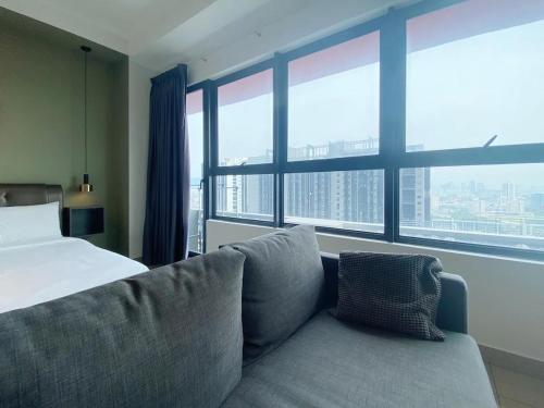Un dormitorio con una cama y un sofá y ventanas. en Arte plus by dream stay, en Kuala Lumpur