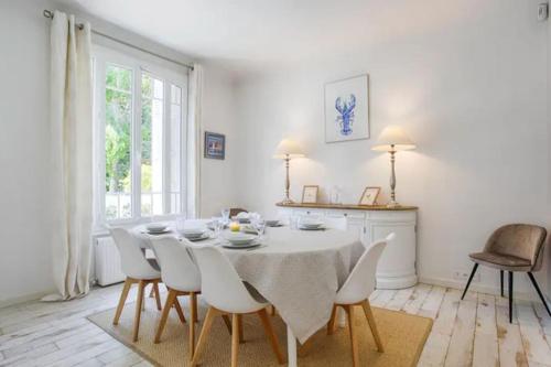 une salle à manger blanche avec une table et des chaises blanches dans l'établissement La charmante maison blanche, à Deauville