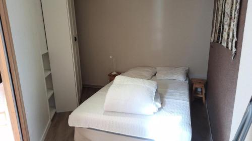 Cette petite chambre comprend un lit avec des draps et des oreillers blancs. dans l'établissement Résidence St Moritz - STM601 - GRAND STUDIO 5 PERSONNES VUE PISTES MAE-2544, à Les Prés