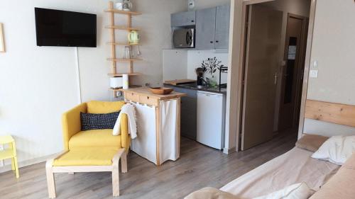 un salon avec une chaise jaune et une cuisine dans l'établissement Résidence St Moritz - STM601 - GRAND STUDIO 5 PERSONNES VUE PISTES MAE-2544, à Les Prés
