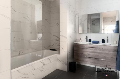une salle de bain blanche avec une baignoire et un lavabo dans l'établissement Résidence Ariondaz Bleuet - Un penthouse au sommet, à Courchevel 1650 MAE-2404, à Courchevel