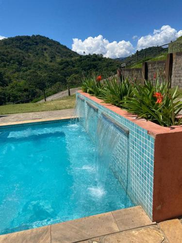 a swimming pool with blue water and plants at Pousada Vale das Araucárias in Santo Antônio do Pinhal