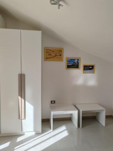 a white room with two benches and paintings on the wall at B&B Colli Ameni in Candela
