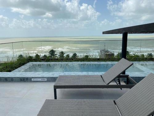 a swimming pool with a table and chairs and the ocean at Varanda do Mar - Flat Intermares in Cabedelo