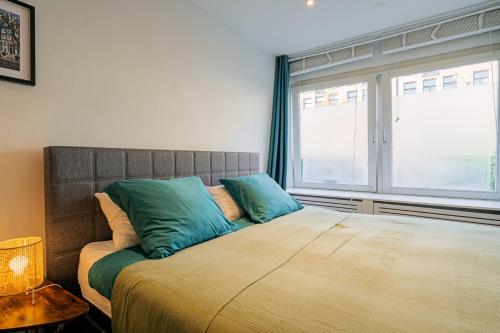 a bedroom with a large bed with blue pillows at Suite with private bathroom near Vondelpark in Amsterdam