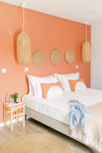 a bedroom with a large bed with an orange wall at Casa dos Rosas in Gavião