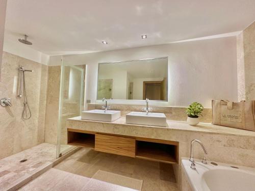 a bathroom with two sinks and a tub and a mirror at Depto. playa y confort amenidades frente al mar in Cancún
