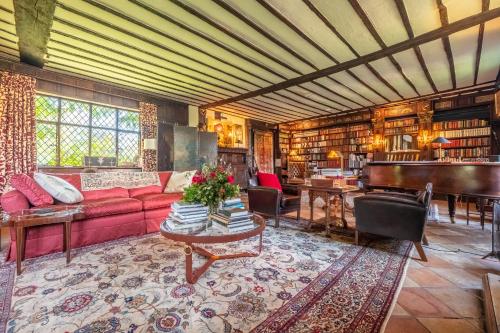 a living room with a red couch and a piano at Spectacular thousand year old Medieval manor house - Flemings Hall in Ipswich