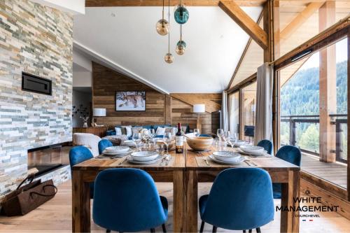 une salle à manger avec une table en bois et des chaises bleues dans l'établissement Résidence Ariondaz Fritillaire - Penthouse de charme vue Vallée MAE-9034, à Courchevel