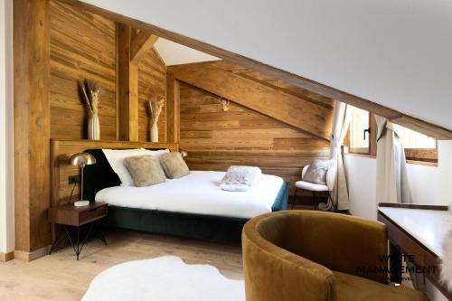 une chambre avec un lit dans une pièce aux murs en bois dans l'établissement Résidence Ariondaz Fritillaire - Penthouse de charme vue Vallée MAE-9034, à Courchevel