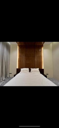 a bedroom with a white bed with a wooden headboard at Jyazelle Resort in Al Ghuţghuţ