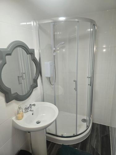 a white bathroom with a shower and a sink at New 4bedroom house near Manchester Airport in Handforth