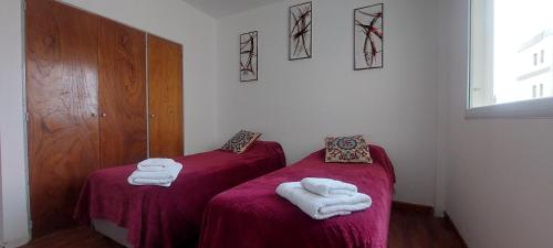 2 camas individuales en una habitación con toallas. en Kattegat, en Puerto Madryn