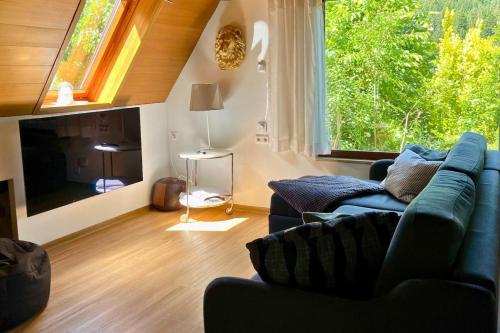 a living room with a blue couch and a large window at Haus Löwe - Komplettes Ferienhaus am Badesee in Erzgrube