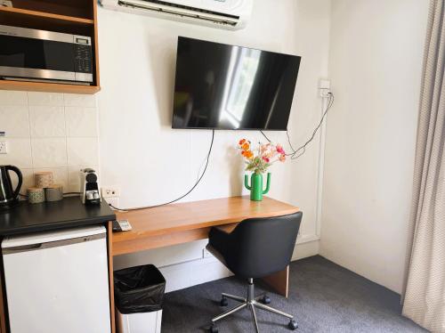 a desk with a television and a vase of flowers on it at 303 Cheerful City Central Crib Sleeps 2 in Perth