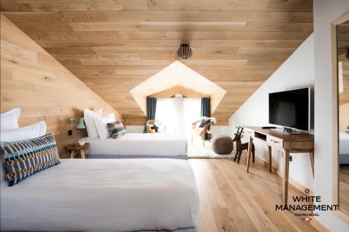 - une chambre mansardée avec 2 lits et une télévision dans l'établissement Résidence Les Glaciers - Superbe duplex vue Vallée à Courchevel 1650 MAE-5251, à Courchevel