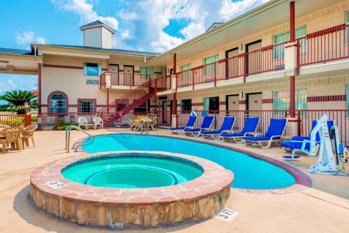 a pool in front of a hotel with blue chairs at Hill Country Inn & Suites - New Braunfels, Gruene in New Braunfels