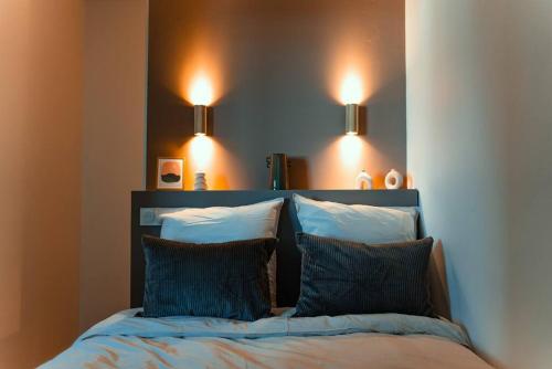 - un lit avec 2 oreillers et 2 lumières au-dessus dans l'établissement Cocon clermontois - Moderne et cosy, à Clermont-Ferrand