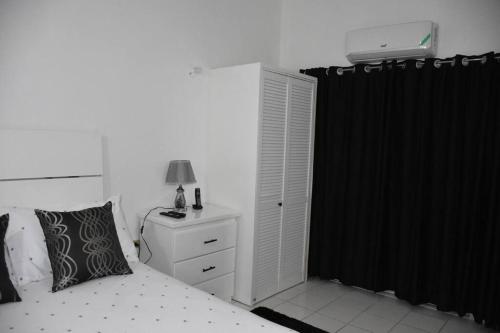 a bedroom with a white bed and a black curtain at White River Apartment 9, Great Pond- Ocho Rios in Stanmore Grove