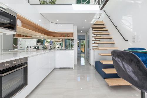 une cuisine avec des placards blancs et un escalier avec des sièges bleus dans l'établissement Village Naturiste R4N - La Villa GreenWood, au Cap d'Agde