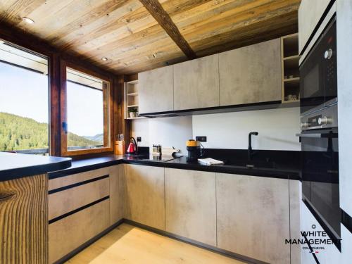 Il comprend une cuisine dotée d'un comptoir noir et de plafonds en bois. dans l'établissement Résidence Ariondaz DaphnÉe - Appartement montagnard moderne pour 4 personnes MAE-8971, à Courchevel