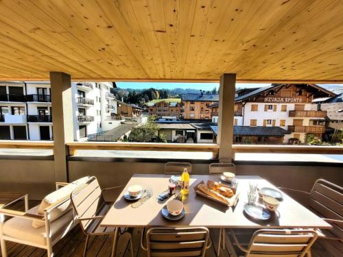 une table sur un balcon avec vue sur une ville dans l'établissement Résidence Essentiel - Appartement neuf, 6 personnes au centre MAE-1061, aux Gets