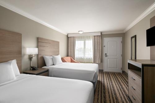 a hotel room with two beds and a television at Solara Inn and Suites in Anaheim