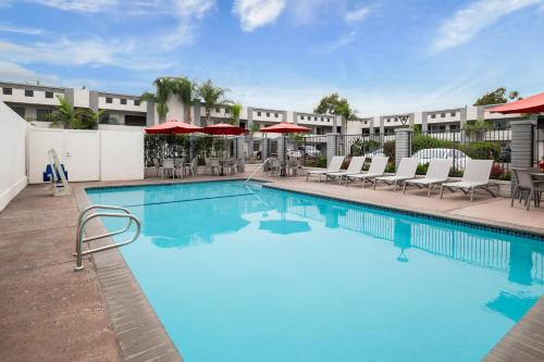 a pool at a hotel with chairs and umbrellas at Solara Inn and Suites in Anaheim