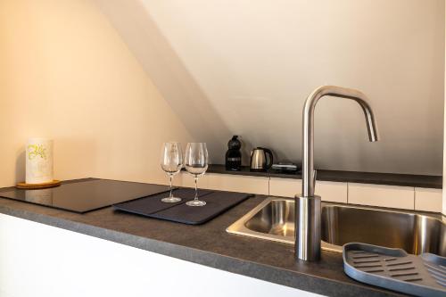 a kitchen counter with two wine glasses and a sink at Via Alpina Apartments with sauna in Mojstrana