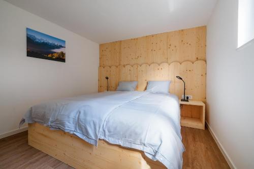 a bedroom with a large bed with a wooden headboard at Via Alpina Apartments with sauna in Mojstrana