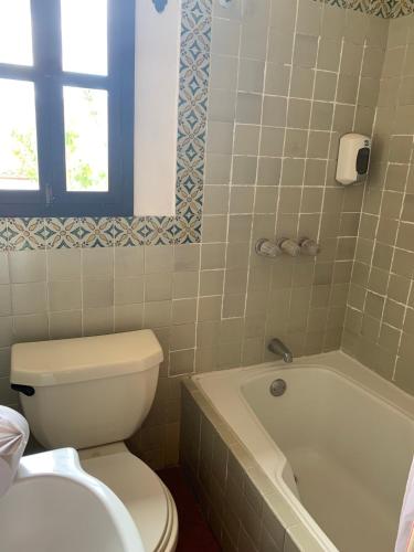 a bathroom with a toilet and a tub and a sink at Hotel T KON T in Antigua Guatemala