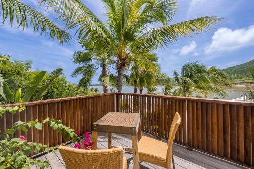 a table and chairs on a deck with a view of the water at La Villa Hibiscus, Saint Martin in Cul de Sac