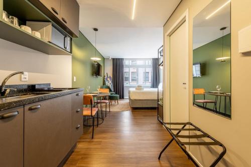 a kitchen with a sink and a room with a bed at Xtay Cais Rooftop - Estúdios Completos com Wifi e academia, no Centro Histórico de Porto Alegre in Porto Alegre