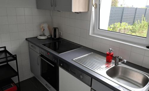 eine kleine Küche mit Spüle und Fenster in der Unterkunft Haus im Garten in der Nähe von Köln-Messe in Bergisch Gladbach