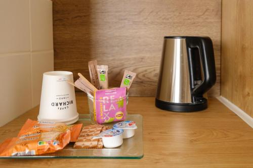 a counter top with a coffee maker and some food at Hotel Tambourin in Vitry-le-François
