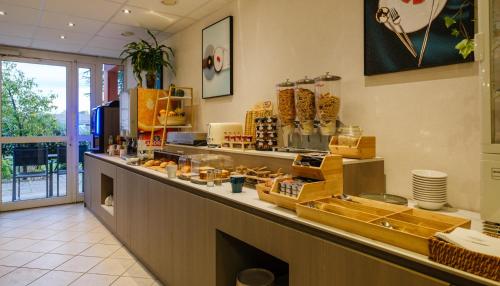 a restaurant with a counter with food on it at Hotel Tambourin in Vitry-le-François