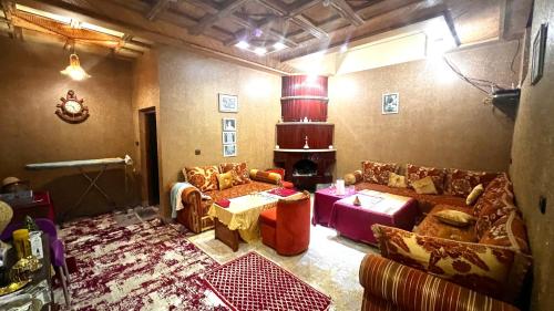 a living room with couches and a fireplace at Dar Calme Chez El Bouhali in Skoura
