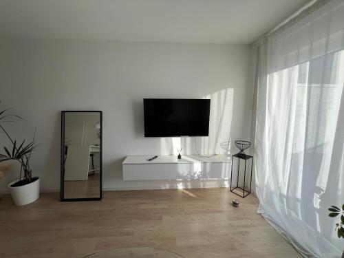 a white living room with a flat screen tv and a mirror at Luxus Wohnung in Schönefeld an Berlin direkt am Flughafen in Schönefeld