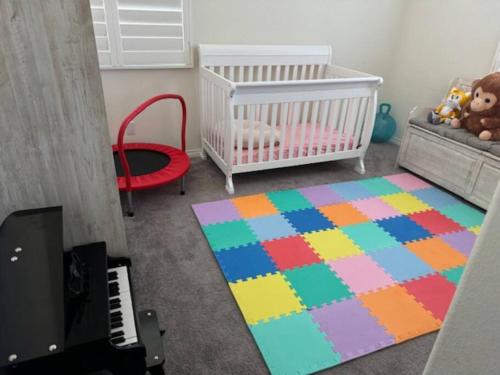 a baby room with a crib and a colorful rug at A Tranquil Haven with Elegance in Menifee