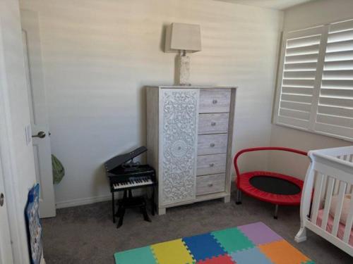 a bedroom with a dresser and a bed and a crib at A Tranquil Haven with Elegance in Menifee