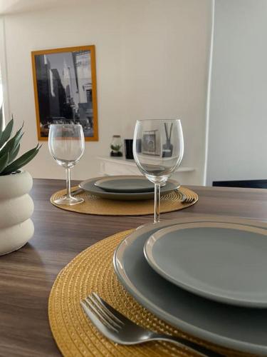 a wooden table with two plates and two wine glasses at Duplex le Brooklyn en Plein centre de Mordelles in Mordelles