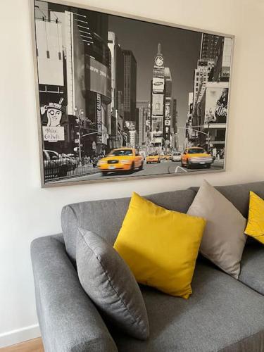 a gray couch with yellow pillows in a living room at Duplex le Brooklyn en Plein centre de Mordelles in Mordelles